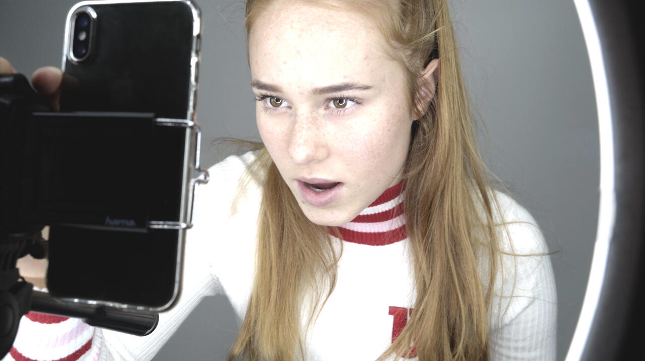 En tonåring som tittar in i sin mobilkamera