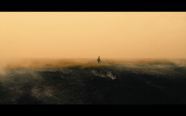 Person i ett landskap omgiven av rök